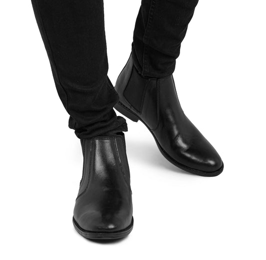 Rash Enterprise men's black leather chelsea boots styled with black pants on white background